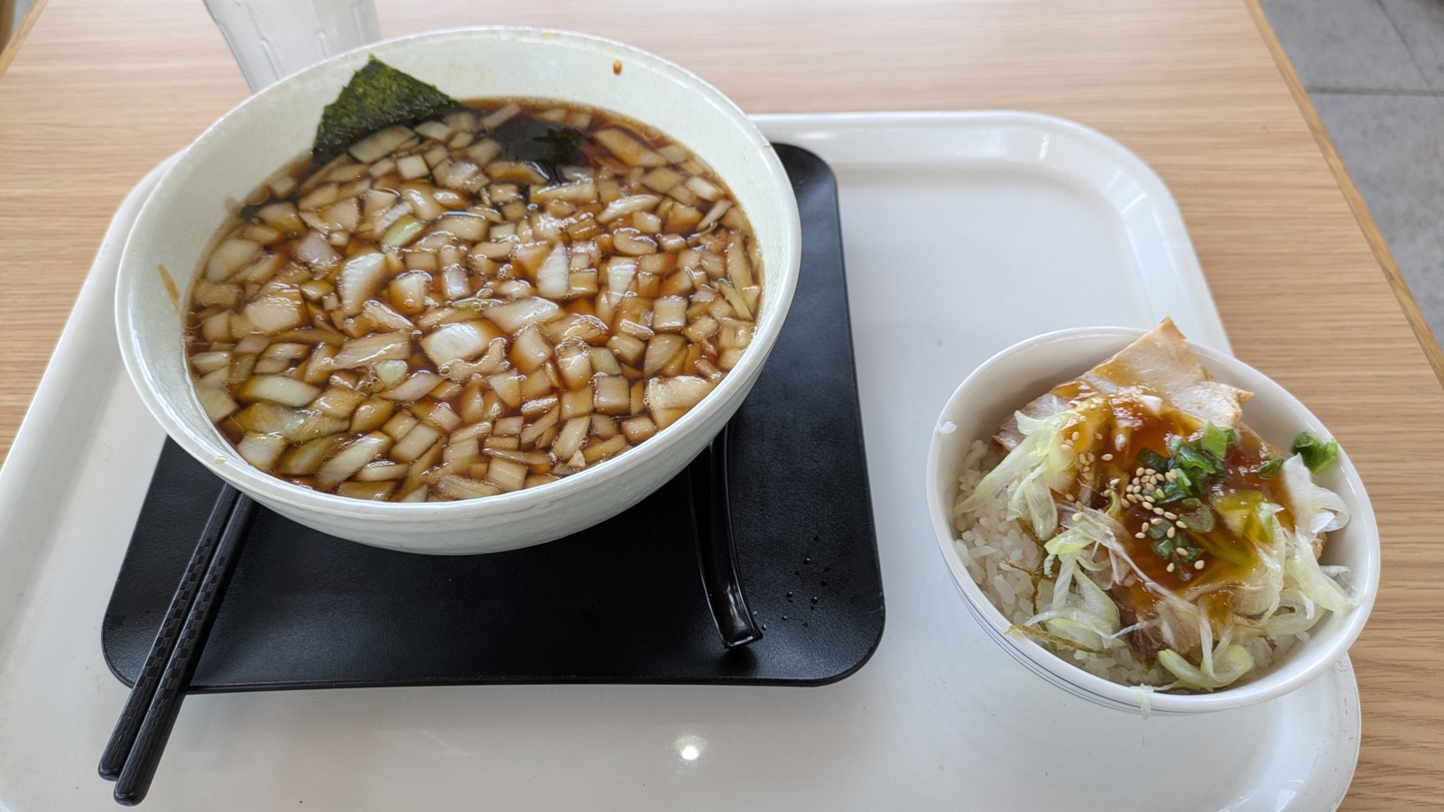 黒いスープの表面を角切りの玉ねぎが覆うラーメンと、ネギとタレをのせたミニチャーシュー丼