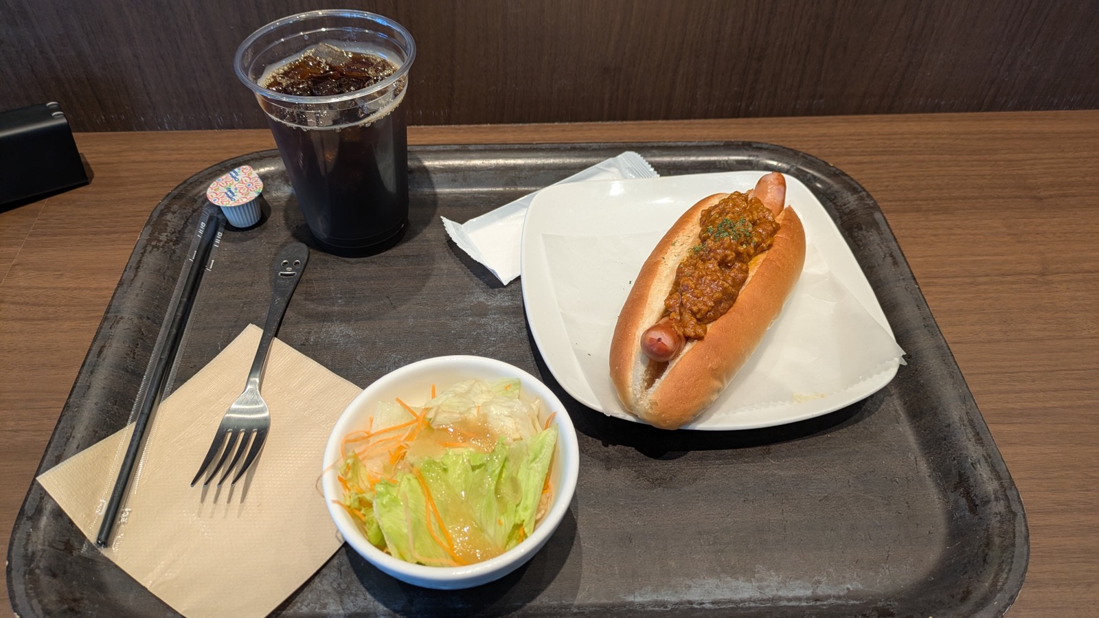 トレイに載ったキーマカレーのホットドッグ、サラダ、アイスコーヒー