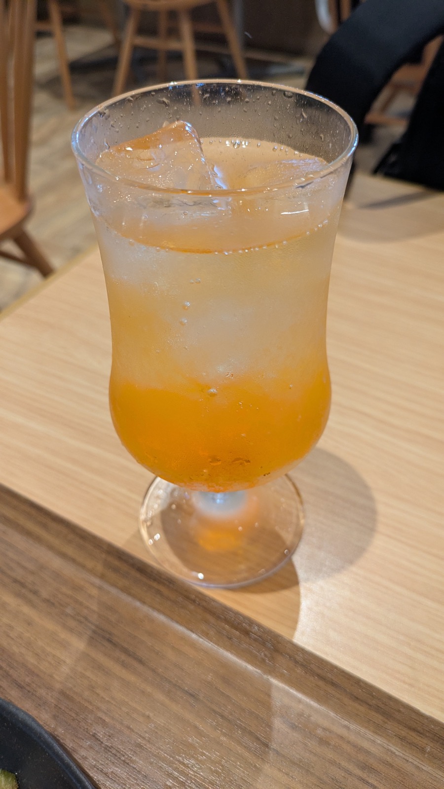 氷入りのグラスに注がれたオレンジ色のドリンク