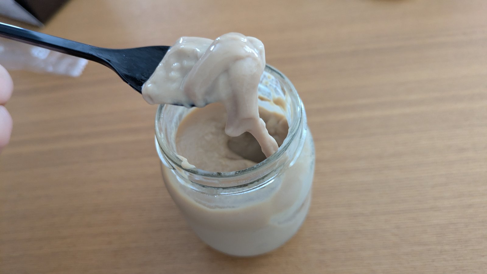 ガラス瓶に入ったコーヒーみるくプリンをスプーンですくったところ