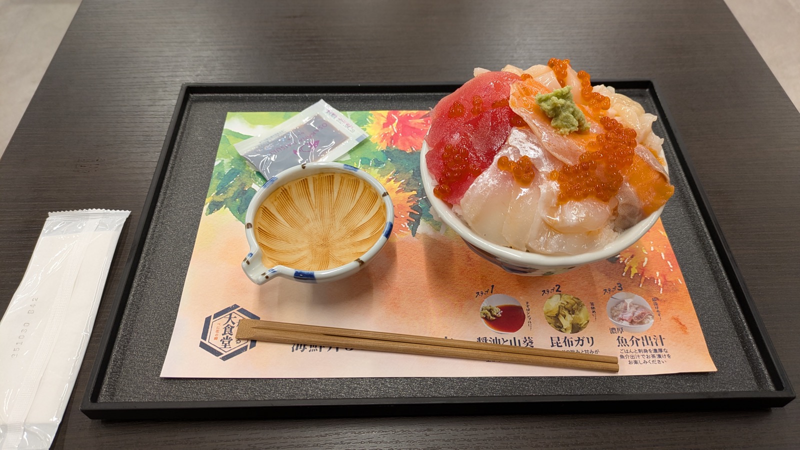 刺身といくらを盛った海鮮丼と、出汁の入った器が載ったトレイ