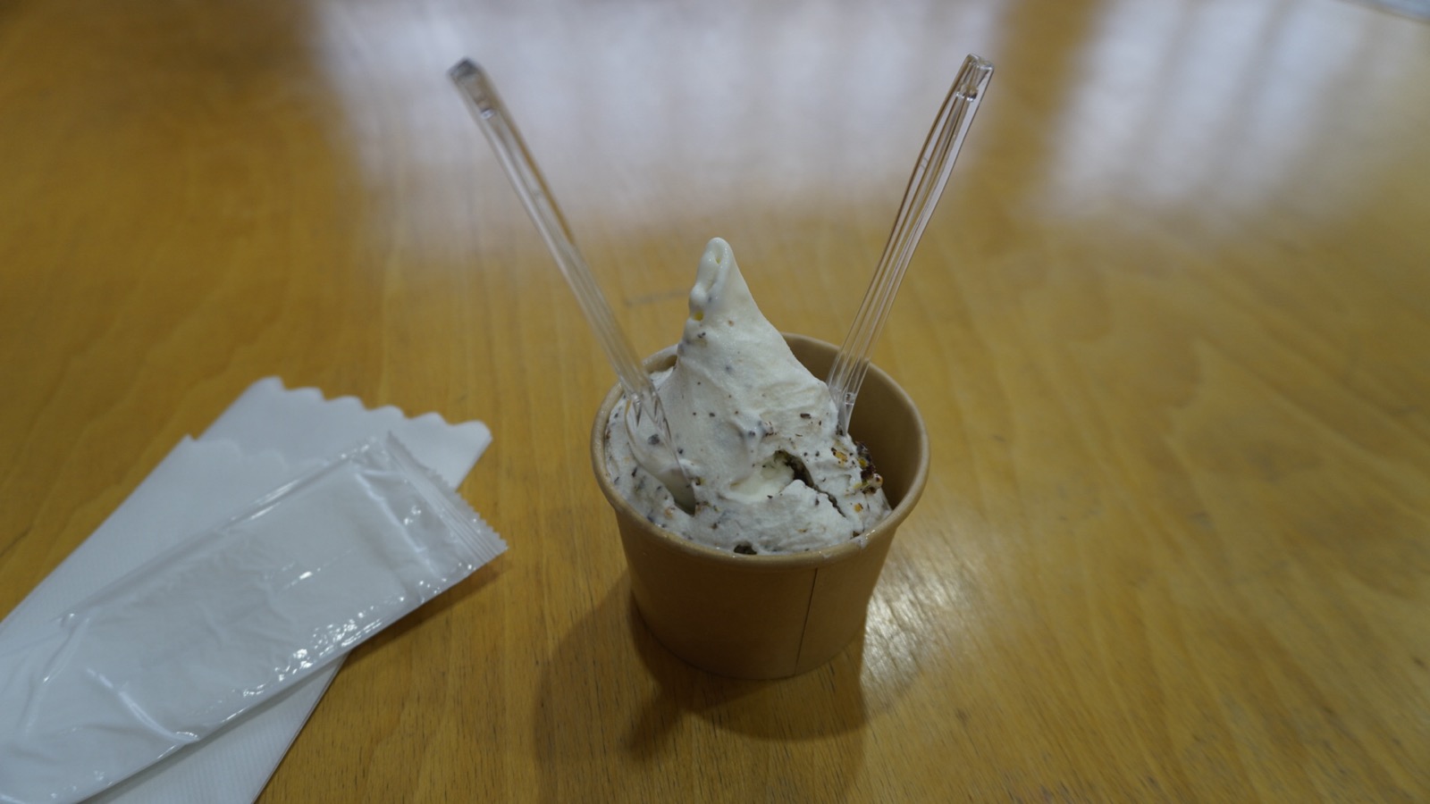 紙カップに盛られた白いジェラート。細かく砕いたナッツが全体に混ざっている