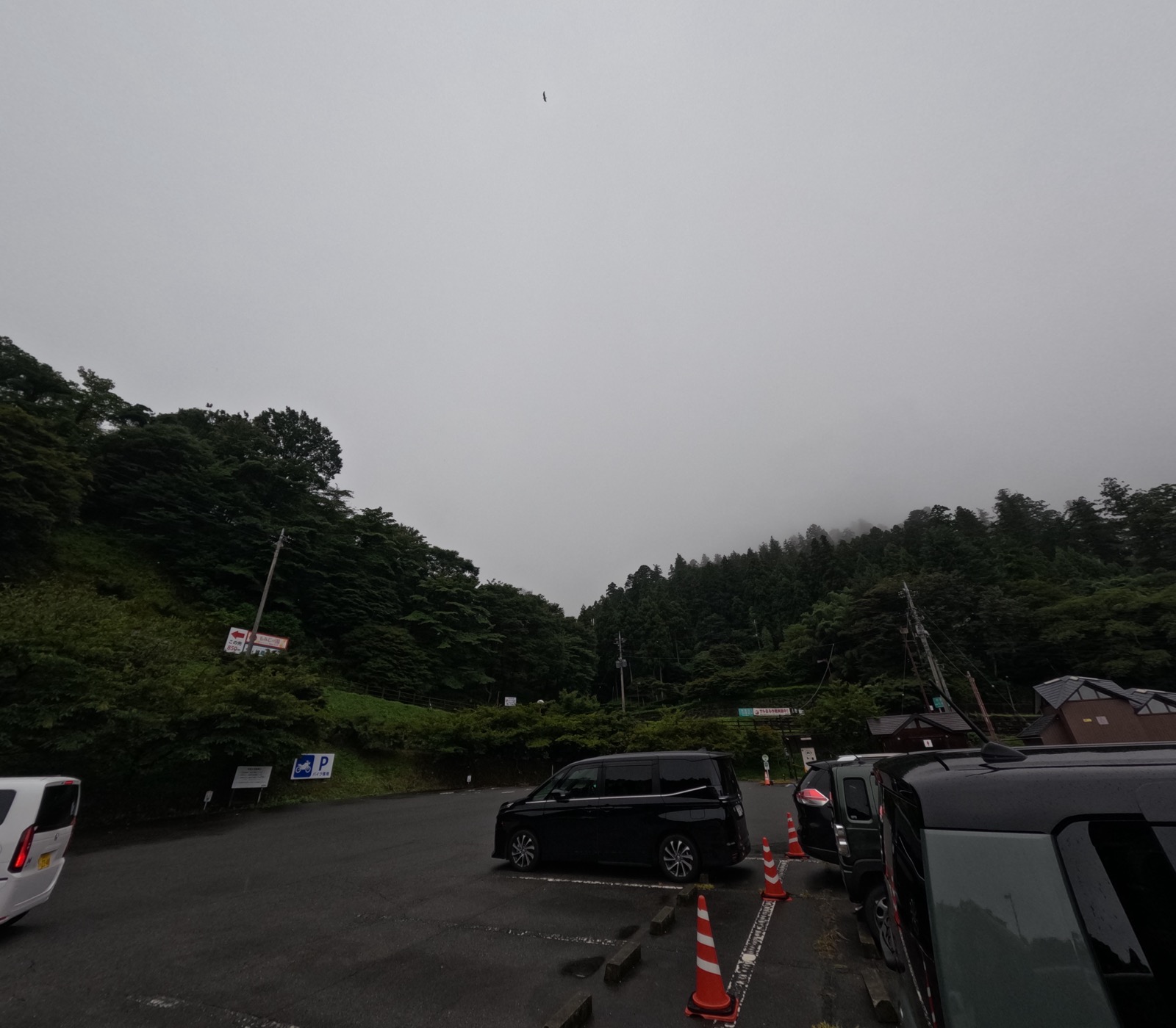 小雨の降る駐車場と、雲に隠れた妙義山