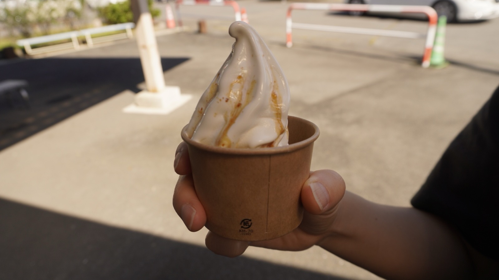 紙カップに入ったソフトクリーム。表面に茶色いソースがかかっている