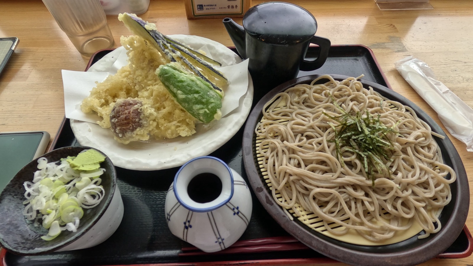 盆に載ったざるそばと、鮎・ナス・ピーマン・しいたけの天ぷら、ねぎとわさびの薬味、そばつゆ