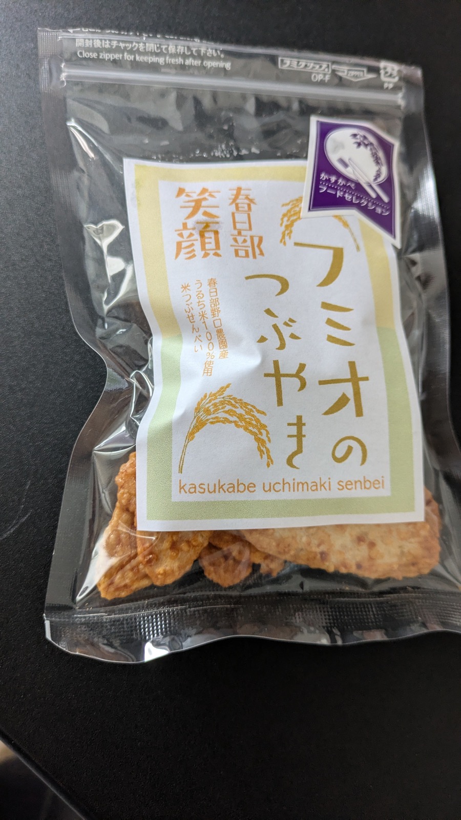 「フミオのつぶやき 春日部笑顔」と書かれたパッケージに入った、春日部産うるち米100%使用のつぶせんべい