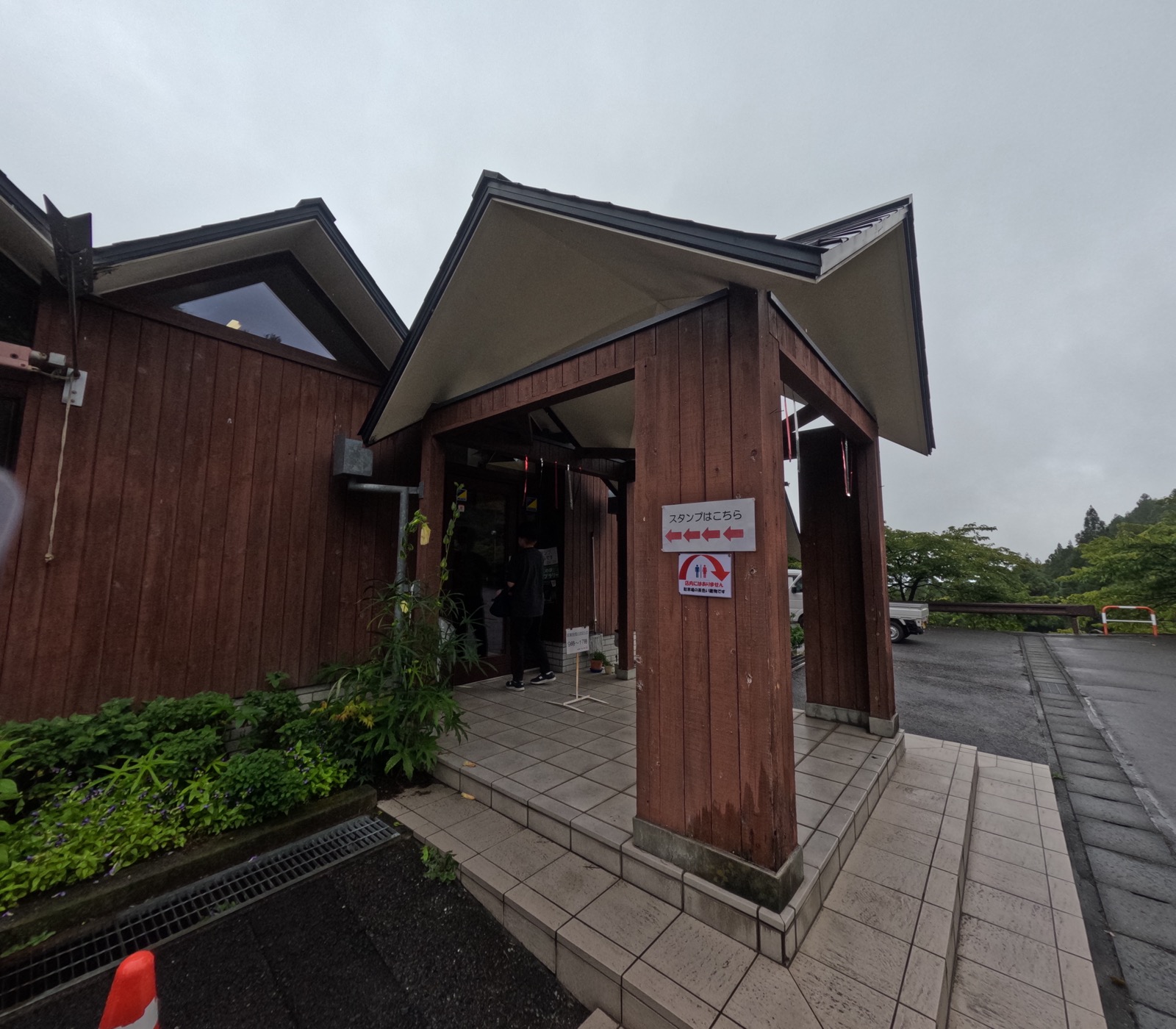 小雨の降る道の駅みょうぎの入口。三角屋根が特徴的な建物が並ぶ。
