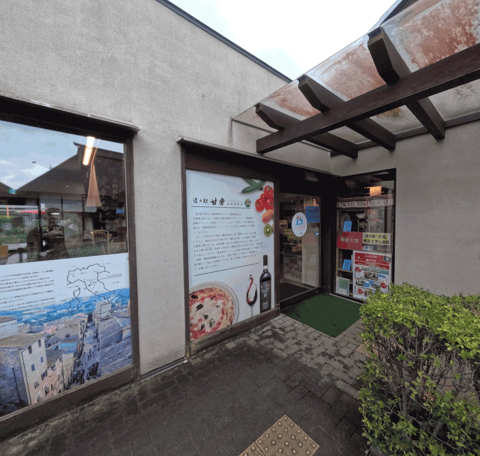 道の駅甘楽の入口。壁にイタリアの地図の入ったパネルと、ピザやトマトの写真が入った施設案内が掲げられている