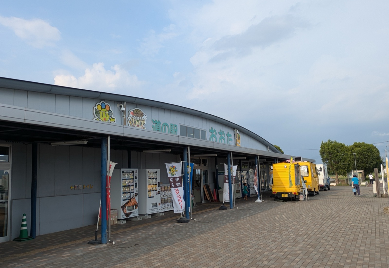 緩やかにカーブした屋根が特徴の「道の駅 おおた」の建物外観。軒下に自動販売機が並び、黄色いキッチンカーが停まっている